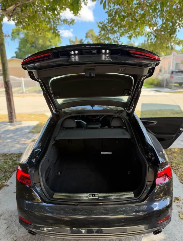 Black Audi R7 with luxury interior and open trunk showing spacious storage.

