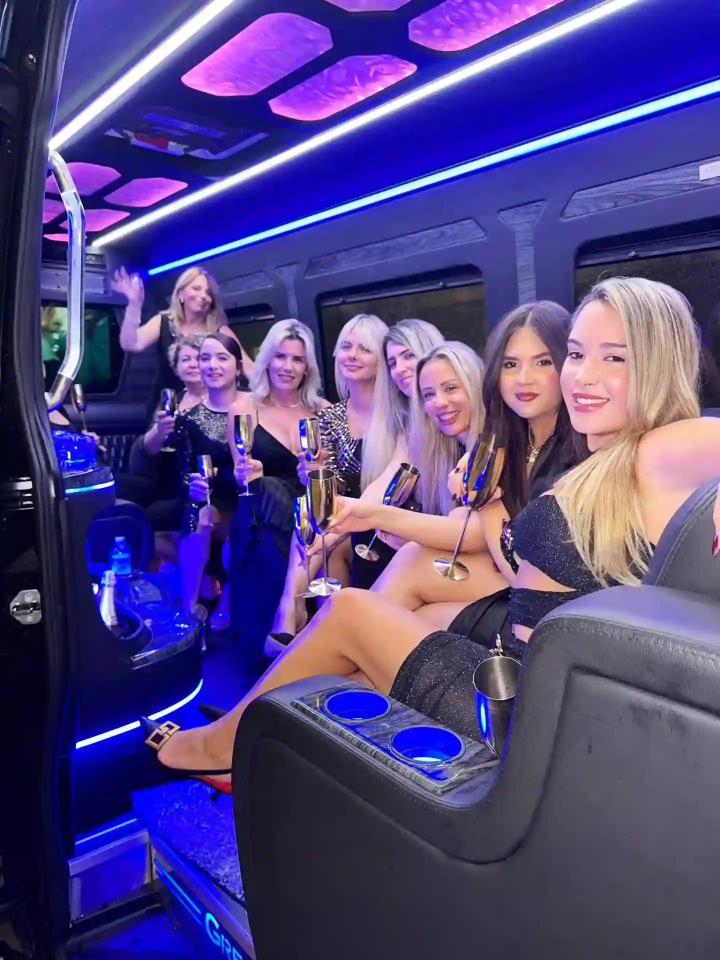 Girls celebrating on a luxury party bus miami, dancing and holding champagne while enjoying a lively and festive group party ride.